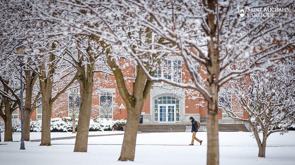 Student walking through the snow at Saint Michael's College