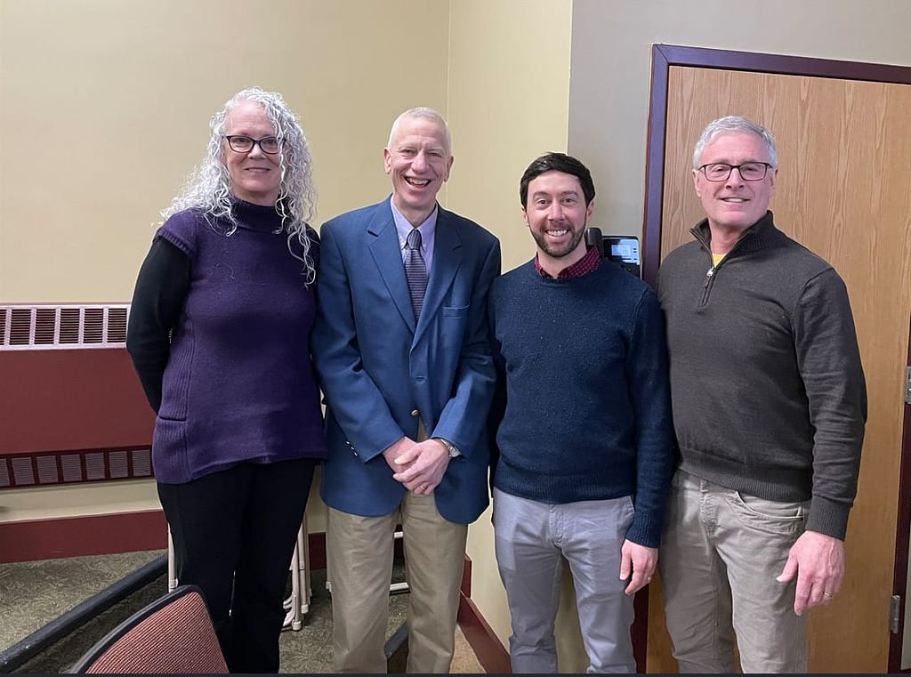 Engineering program alumnus Jason Charest '07, second from right, poses with Mathematics Professors Barbara O'Donovan, left, and George Ashline as well as Saint Michael's College President Richard Plumb, right, following a talk by Charest in January 2025.