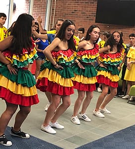 students in bright colored dresses dancing in a line