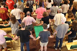 students and parents holding hands during mass service