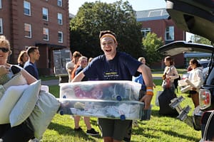 A student poses while carrying containers to help with Move In Day at Saint Michael's College.