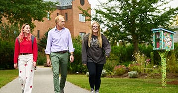 A Saint Michael's College professor walks with two Saint Michael's students through the Teaching Gardens on campus. 