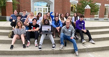 A group of Saint Michael's College students sits on the steps of the Durick Library, which houses the Student Success Center. 