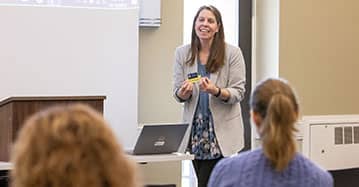 A Saint Michael's College alum stands in front of a group of students. 